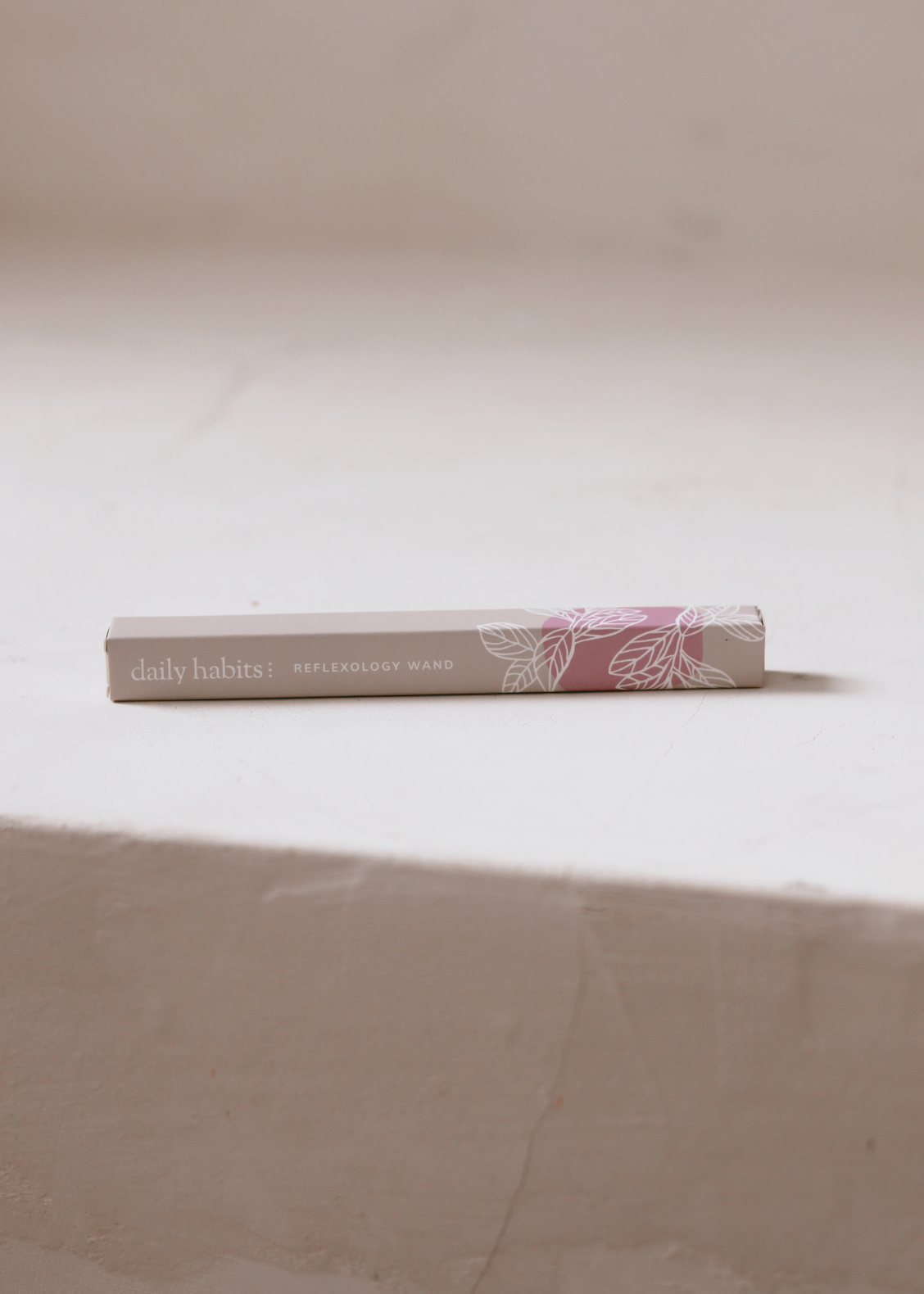 Daily Habits Reflexology Wand box resting on a stone surface.
