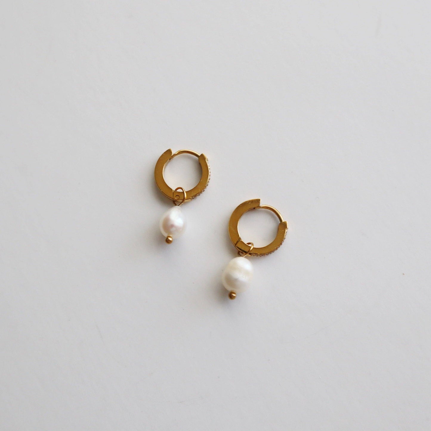 JESSA Jewelry CZ Huggies with Pearl Drop shown side view and slightly apart on a white background to display shape and scale.