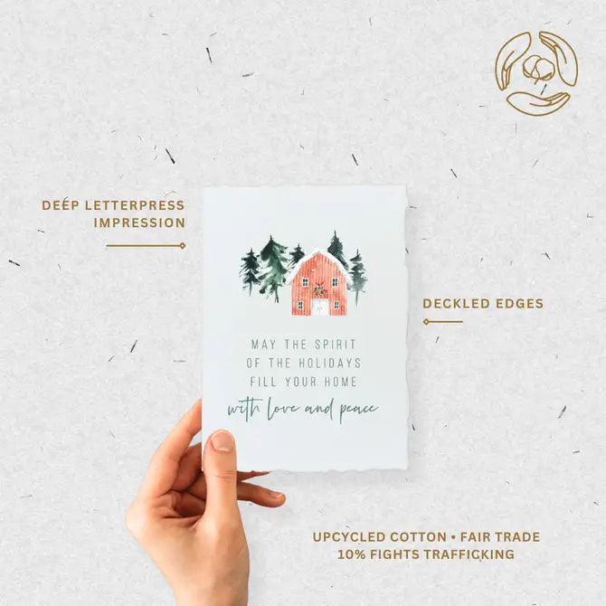 Hand holding eco-friendly holiday card highlighting deep letterpress impression, deckled edges, and fair-trade cotton paper.