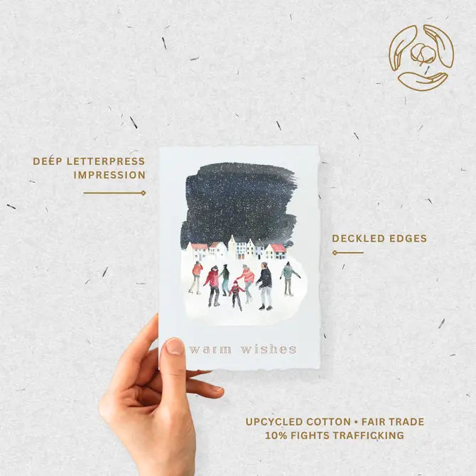 Hand holding eco-friendly holiday card highlighting deep letterpress impression, deckled edges, and fair-trade cotton paper.