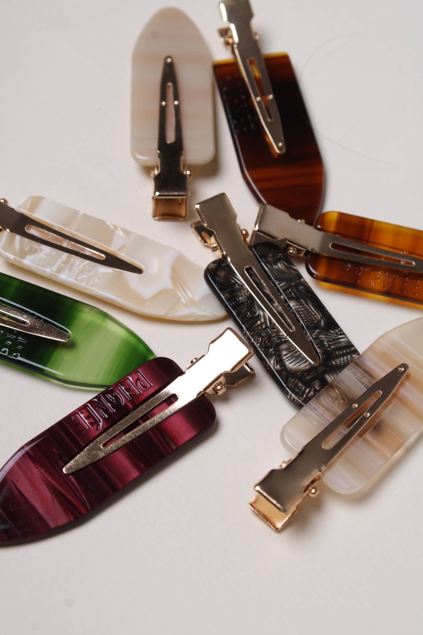 Assorted Peignée Paris creaseless barrette clips in various colors including ivory, green, and tortoise.