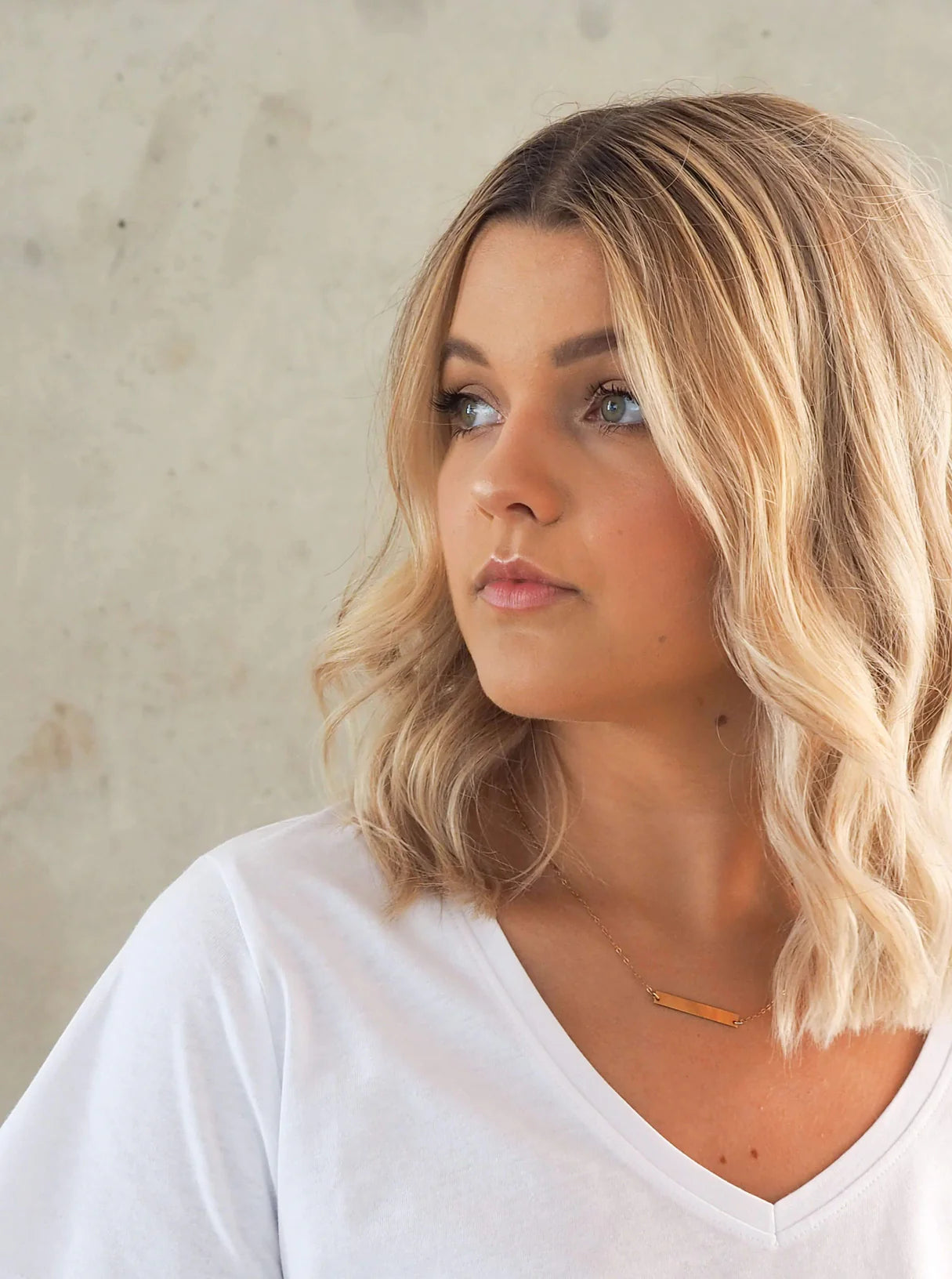 Model with glowing skin and natural makeup wearing a white shirt, showcasing results of The Unnamed Brightening & Anti-Aging Sheet Mask.