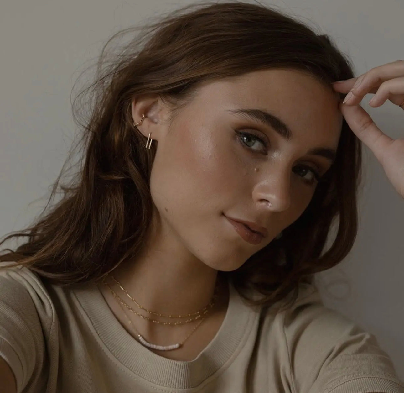 Model wearing Token Jewelry Mini Staples earrings in gold with layered jewelry.