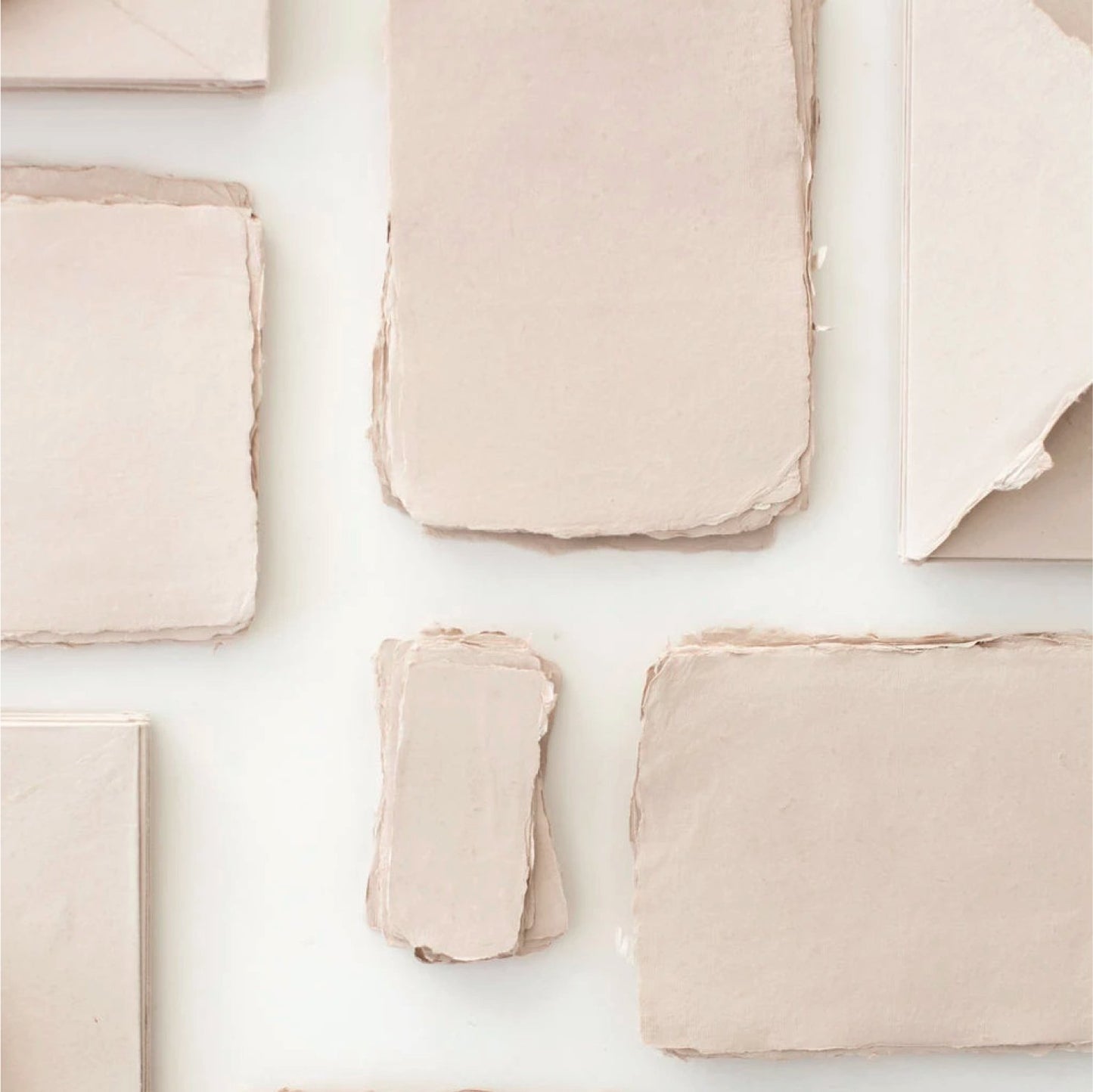 Flat lay of eco-friendly recycled cotton paper sheets showcasing the deckled edges and handmade texture used in Paper Baristas greeting cards.