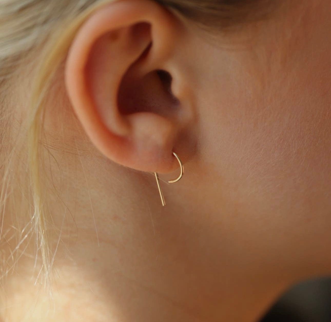 Model with blonde hair wearing Token Jewelry The Nines earrings in gold.
