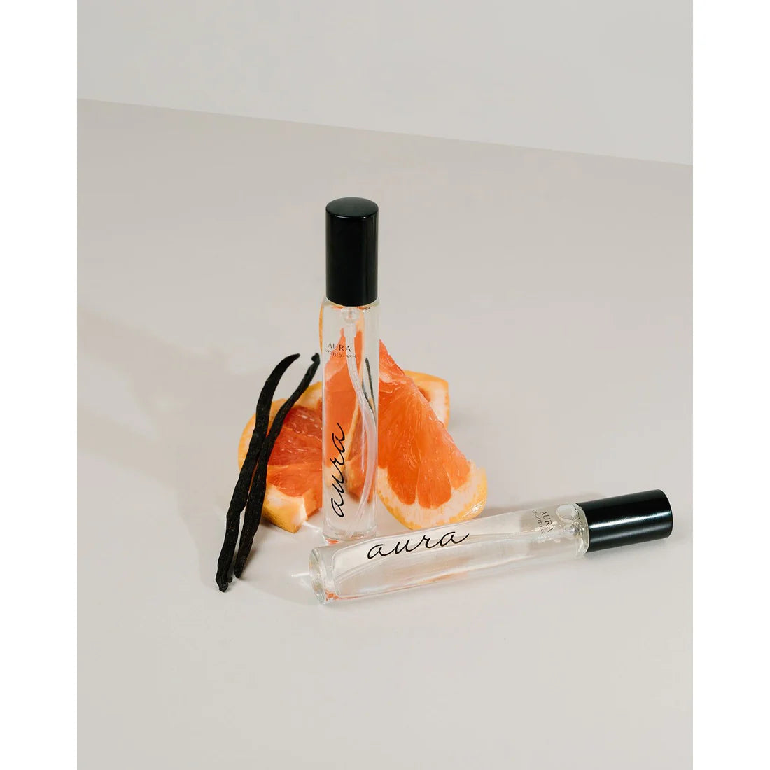 Orchid & Ash Aura travel spray photographed with sliced grapefruit and vanilla bean.