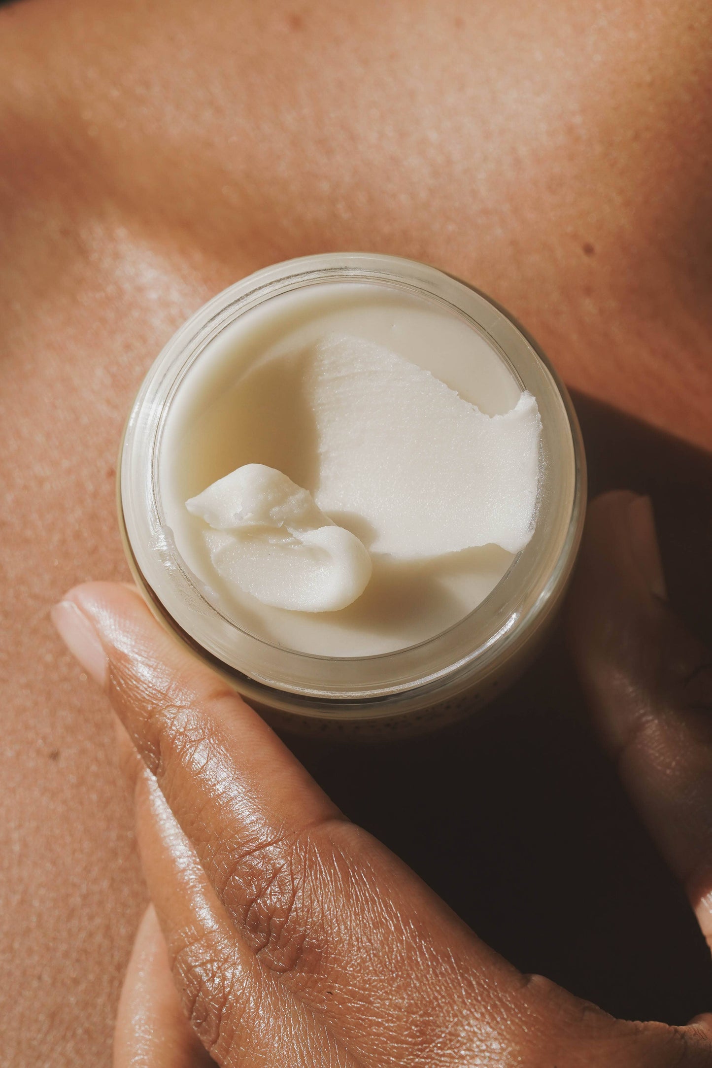 Open jar of Circular Living Whipped Deodorant Gentle Unscented held in hand showing creamy texture.