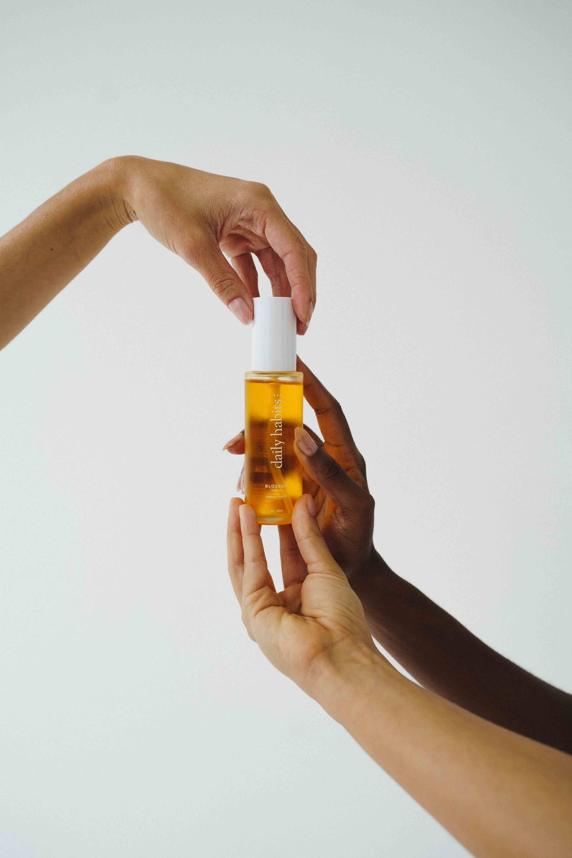 Hands holding Daily Habits Blossom Body Oil emphasizing self-care and gifting