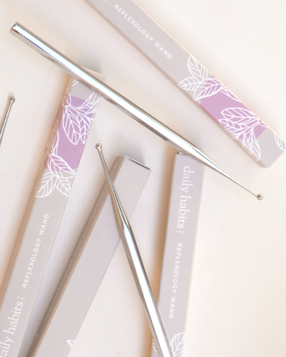 Flatlay of multiple Daily Habits Facial Reflexology Tools with botanical packaging design.
