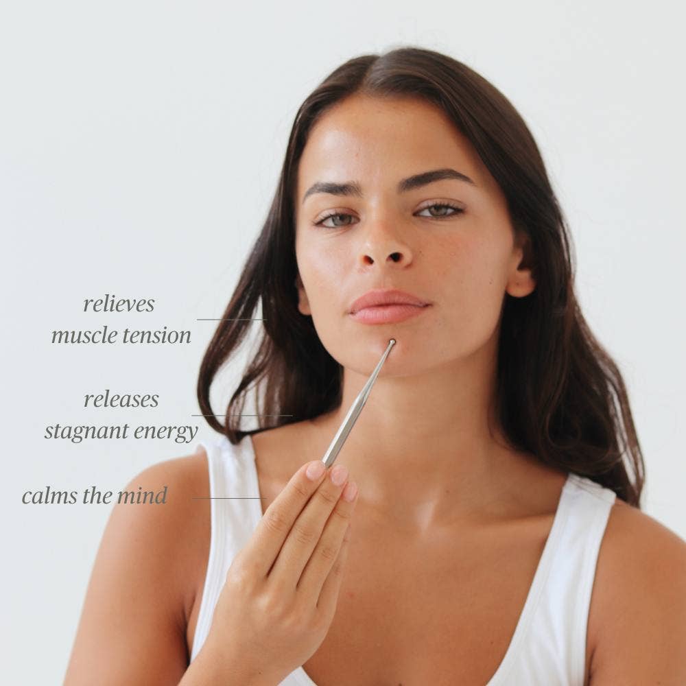 Woman using Daily Habits Facial Reflexology Tool on face to relieve tension and calm the mind.
