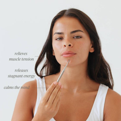 Woman using Daily Habits Facial Reflexology Tool on face to relieve tension and calm the mind.
