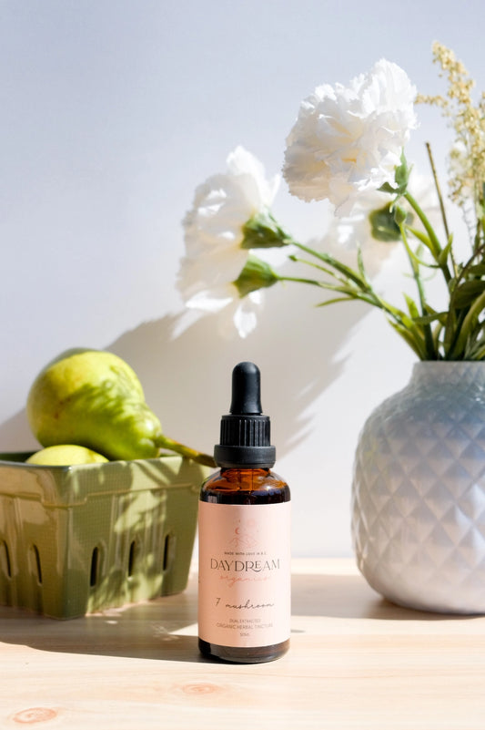 Daydream Organics Seven Mushroom Blend Tincture bottle displayed next to pears and flowers.