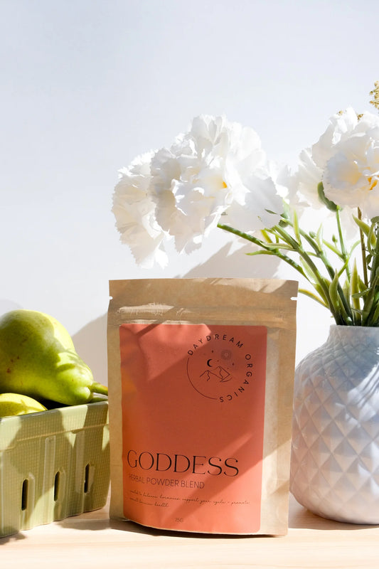 Daydream Organics Goddess Herbal Powder Blend product bag placed on table beside fresh pears and flower vase.