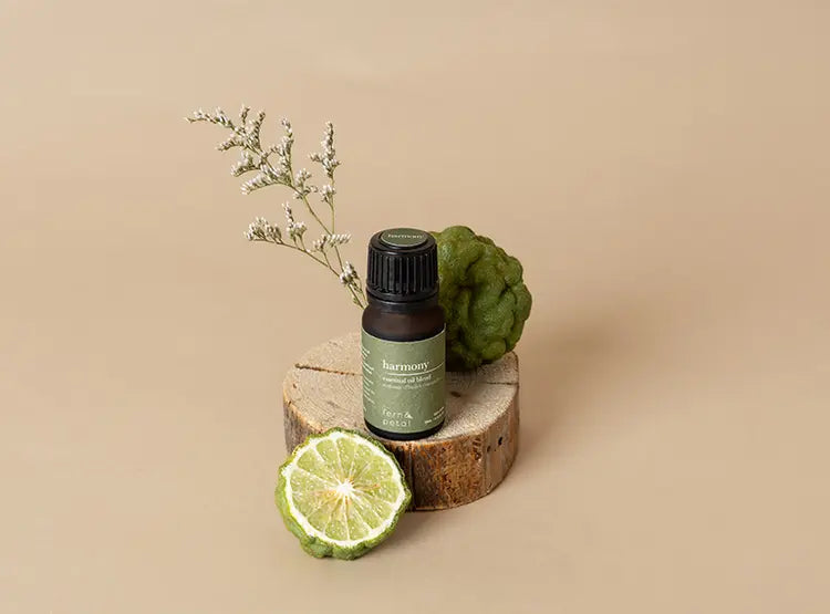 Fern & Petal Harmony Essential Oil bottle on a wooden display styled with lime wedge and flowers against a neutral background.