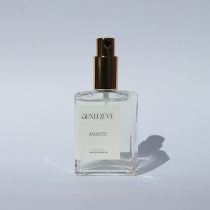 Closed bottle of Genevieve Fragrances Amante perfume with gold spray top on white background.