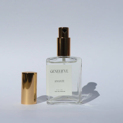 Open bottle of Genevieve Fragrances Amante perfume with gold cap on white background.