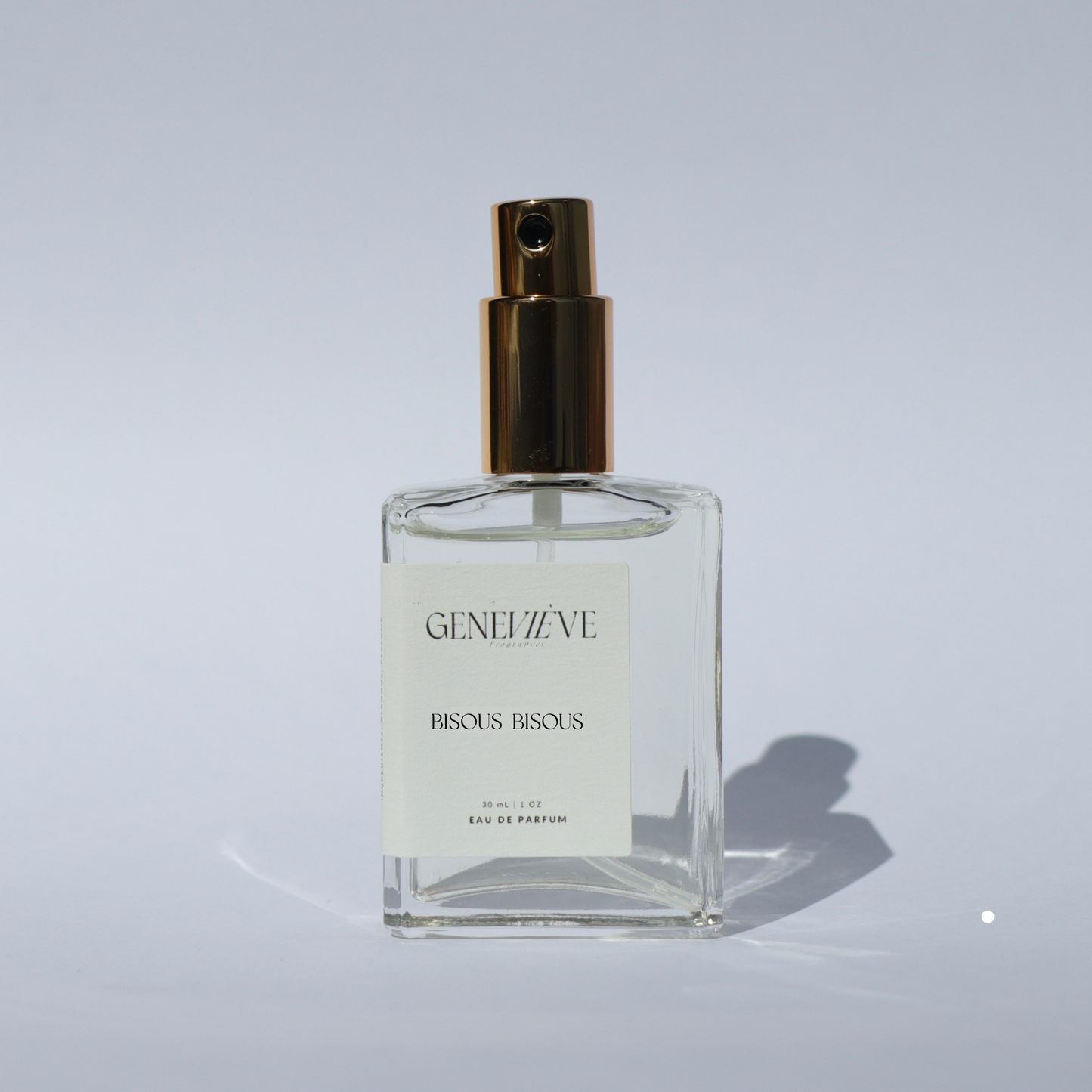 Closed bottle of Genevieve Fragrances Bisous Bisous perfume with open gold spray top on white background.
