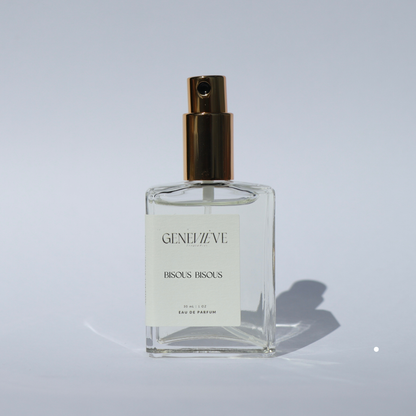 Closed bottle of Genevieve Fragrances Bisous Bisous perfume with open gold spray top on white background.
