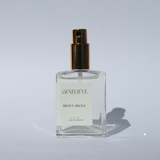 Closed bottle of Genevieve Fragrances Bisous Bisous perfume with open gold spray top on white background.