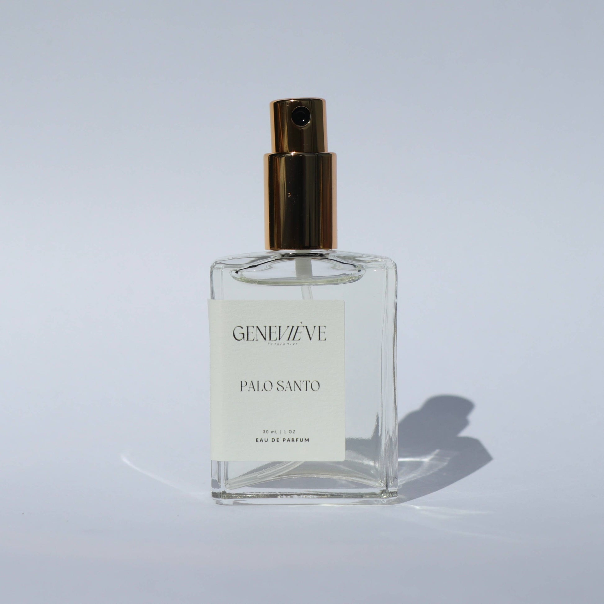 Geneviève Palo Santo Eau de Parfum bottle with spray nozzle open on a white background.