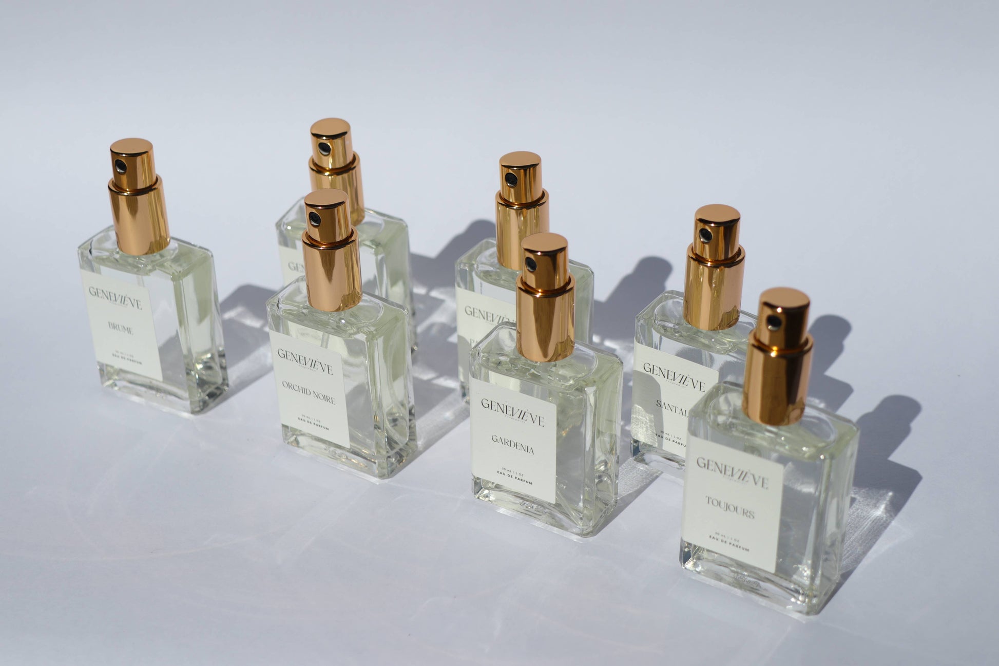 Group of Genevieve Fragrances perfume bottles displayed on white background with shadows.