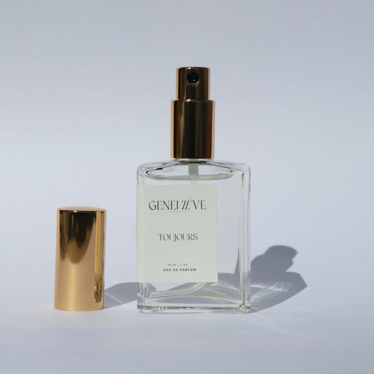 Geneviève Toujours Eau de Parfum bottle with gold cap placed beside it on a white background.