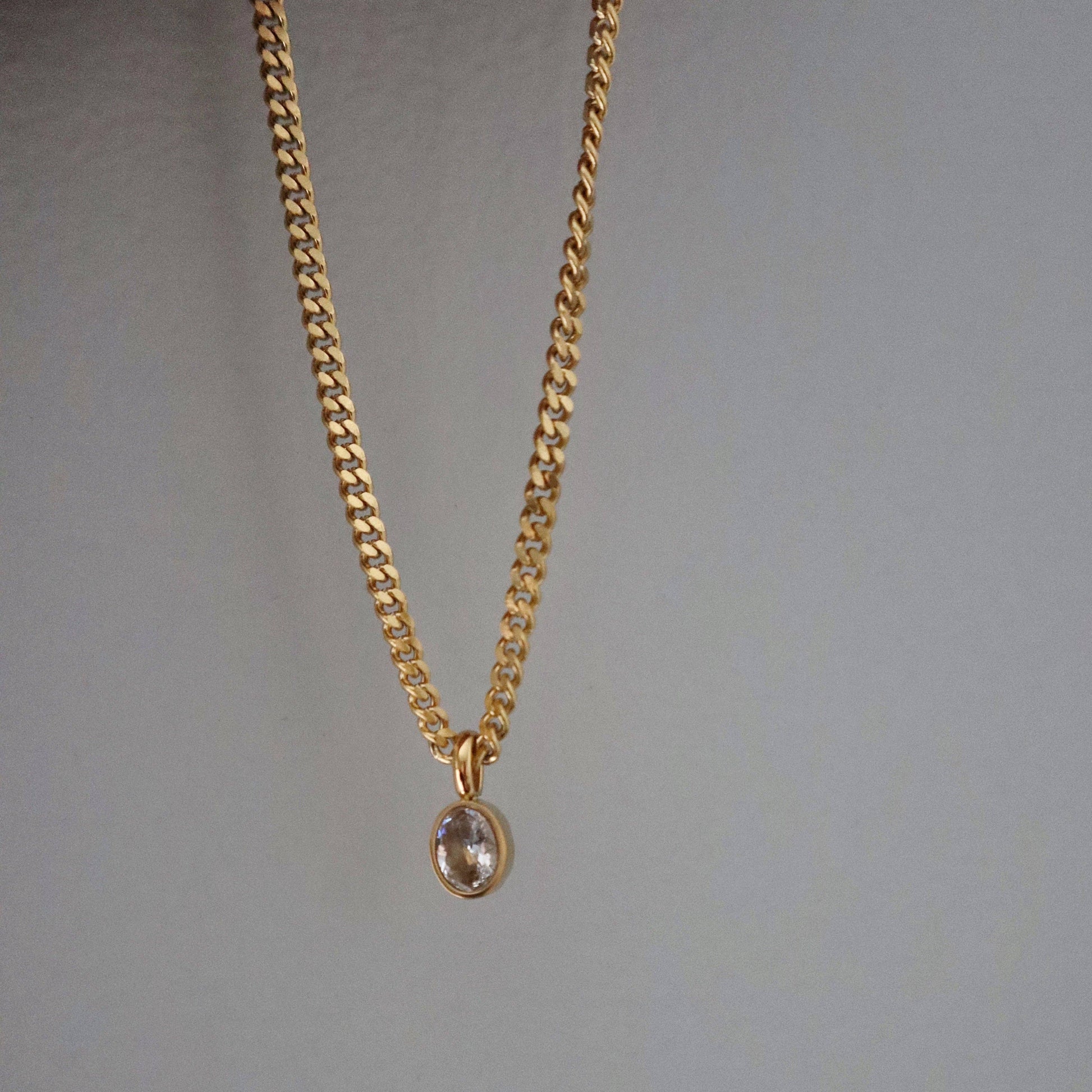 JESSA Jewelry oval CZ pendant necklace hanging vertically, showcasing chain and gem sparkle.