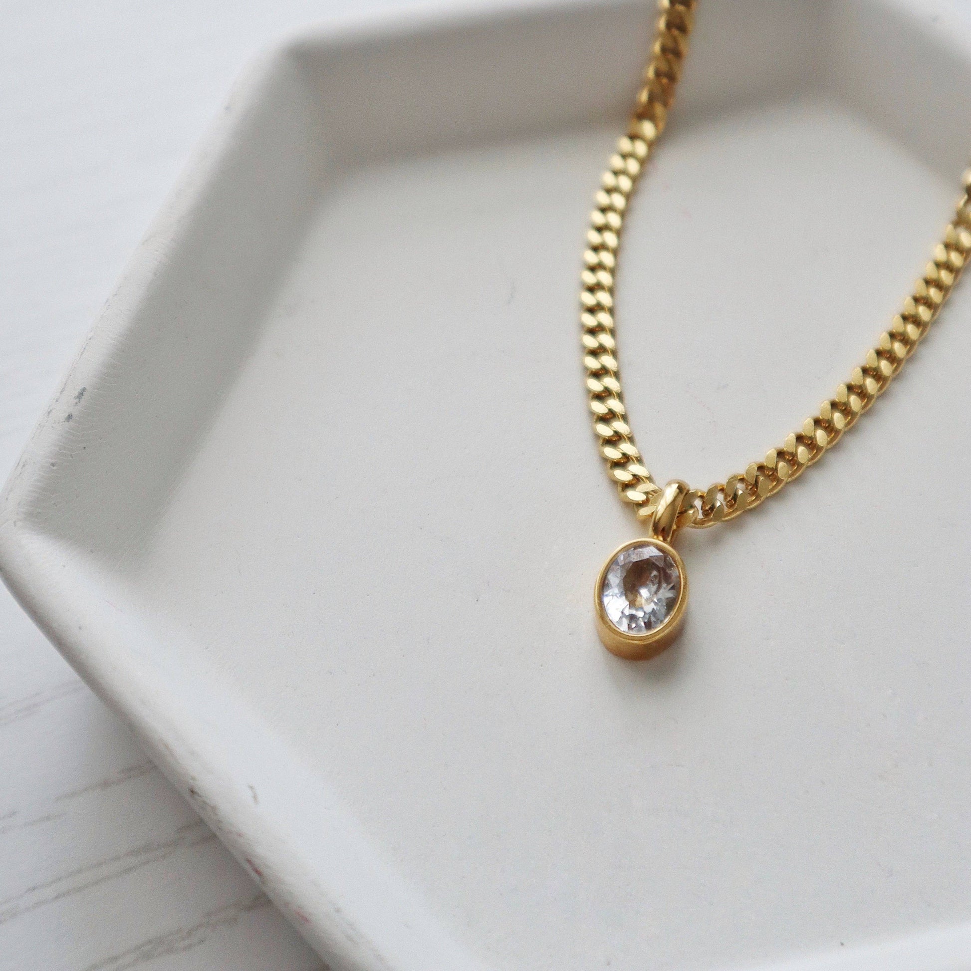 JESSA Jewelry oval CZ necklace styled on a white hexagon tray for minimal presentation.