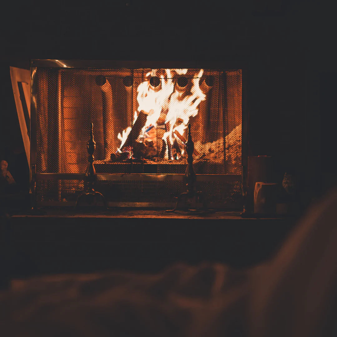 Cozy fireplace with warm flames, evoking the comforting scent of the Hearth candle by Orchid & Ash.