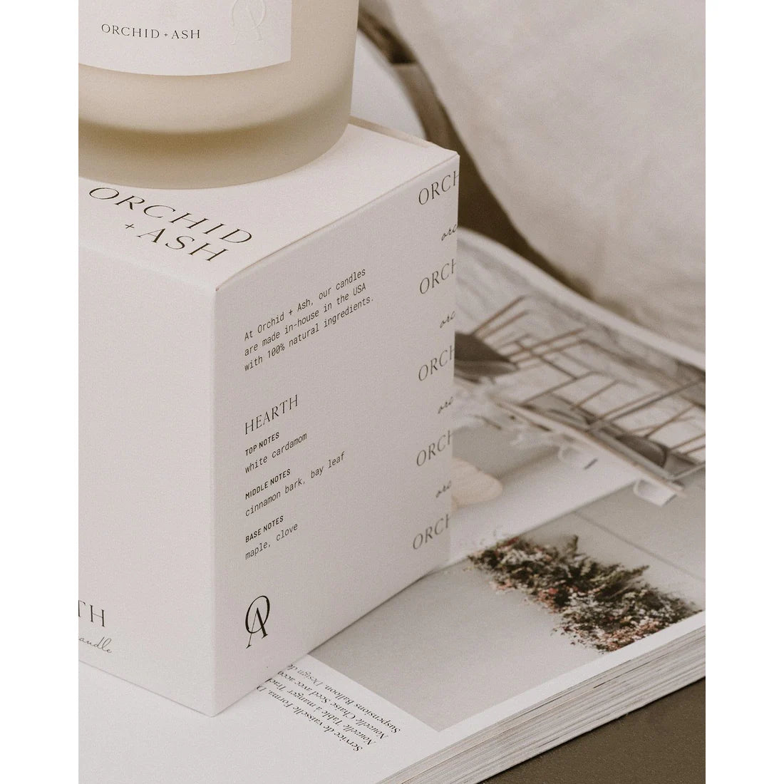 Close-up of Orchid & Ash Hearth candle on its branded box and magazine spread.