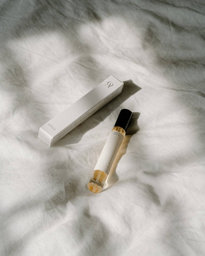 Idyll roller perfume and its box by Orchid & Ash placed on softly wrinkled white linen.