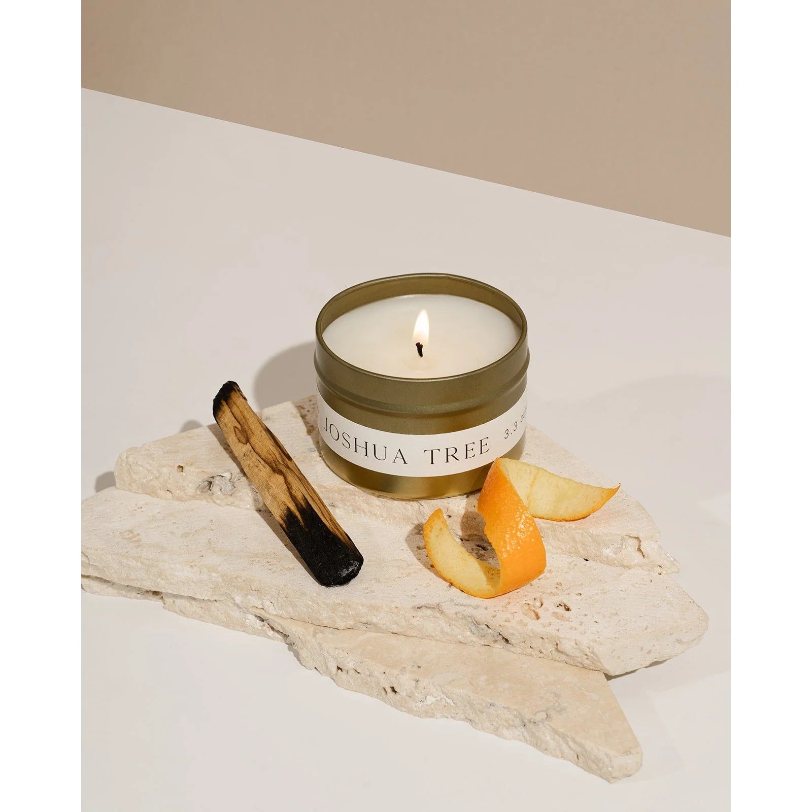 Joshua Tree candle tin by Orchid & Ash styled with burnt palo santo, orange slice and white stone on soft background.