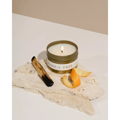 Joshua Tree candle tin by Orchid & Ash styled with burnt palo santo, orange slice and white stone on soft background.