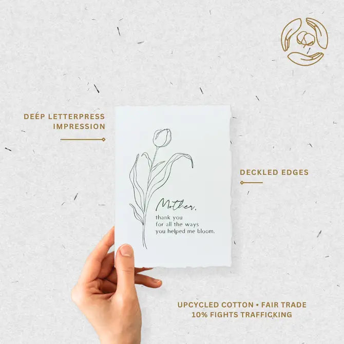 Hand holding eco-friendly greeting card highlighting deep letterpress impression, deckled edges, and fair-trade cotton paper.
