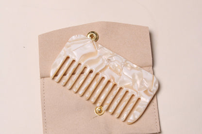  Peignée Paris detangling comb placed on top of its beige suede case with gold button.