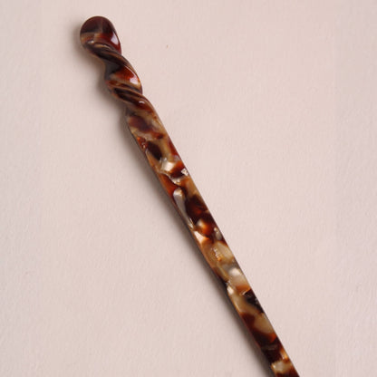 Espresso-colored Peignée Paris hair stick pin shown at a diagonal angle.
