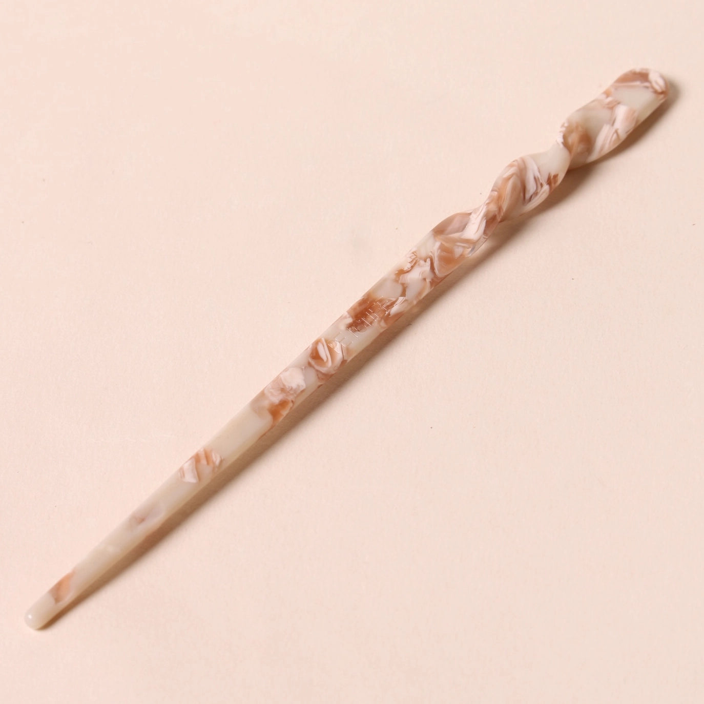 Full view of the Peignée Paris hair stick pin in nougat shade laid flat over neutral background.