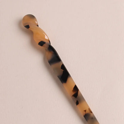 Close-up of the twisted details of the panther colored Peignée Paris hair stick pin on neutral background.