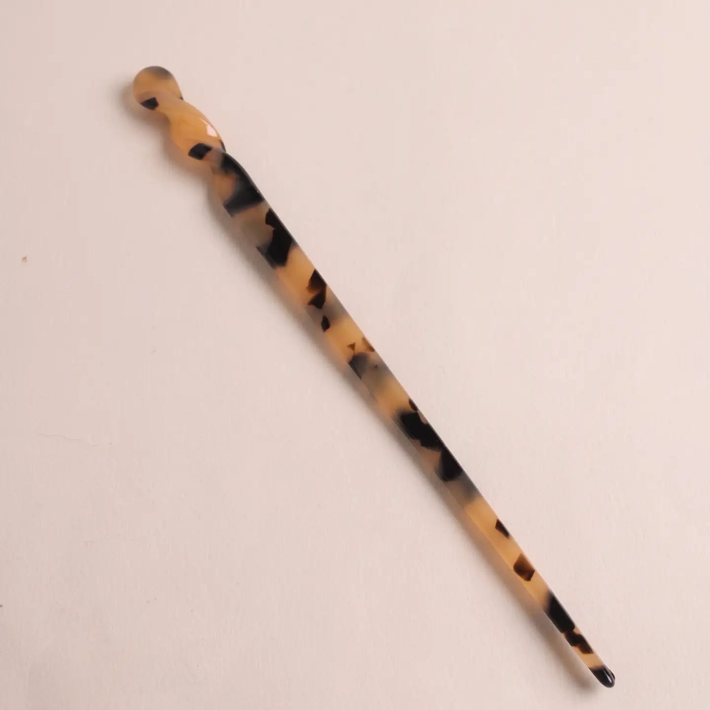 Full view of the panther-patterned hair stick pin from Peignée Paris with curved detailing at top.