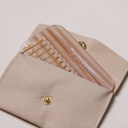 Peignée Paris Latte travel comb partially tucked inside its beige suede pouch.