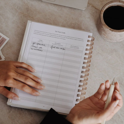 Close-up of hands filling in goal setting intentions in The Self Care Planner, setting personal work, wellbeing and relationship goals.