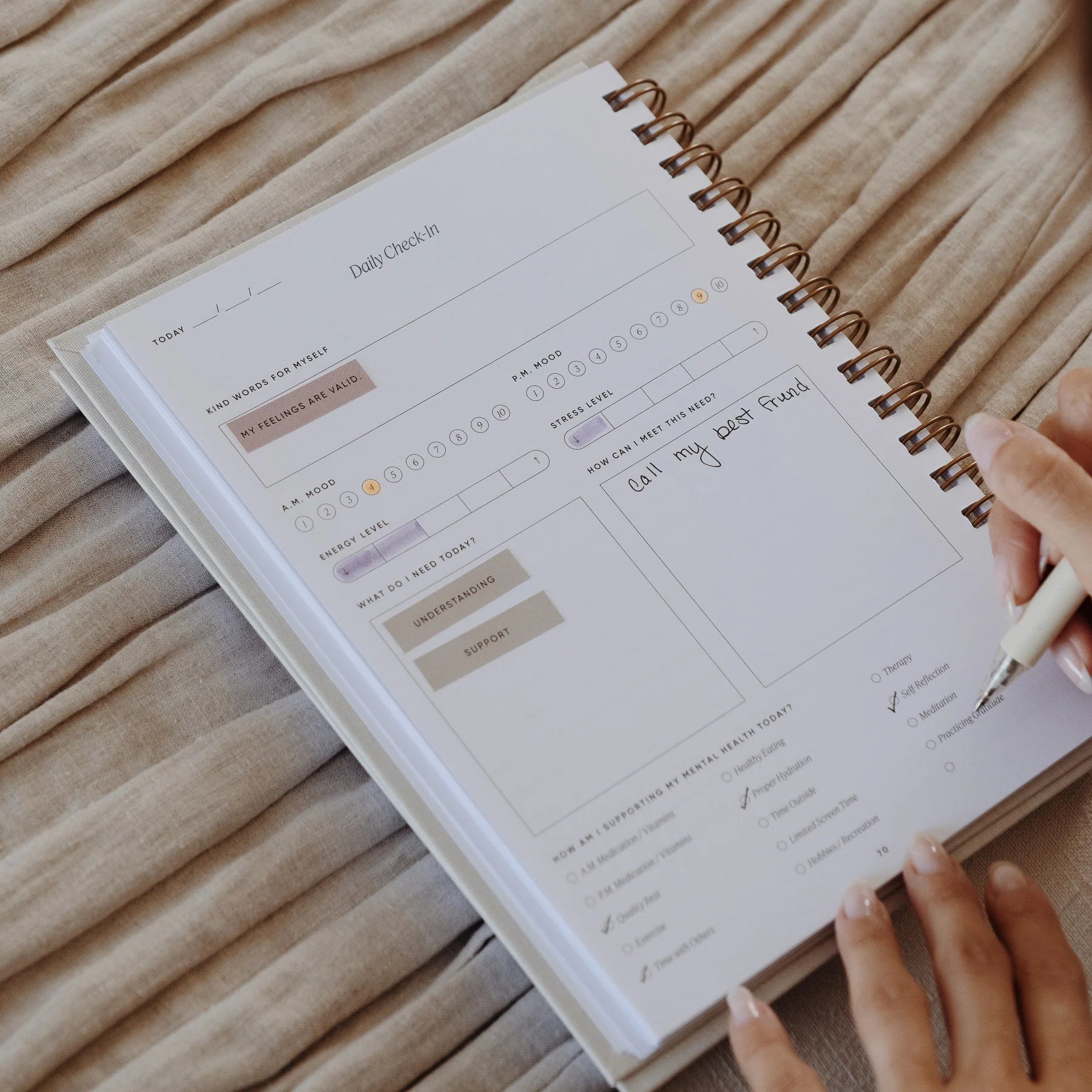 Close-up of The Inner Work Journal open to the daily check-in page, with a hand filling out entries using stickers and notes.