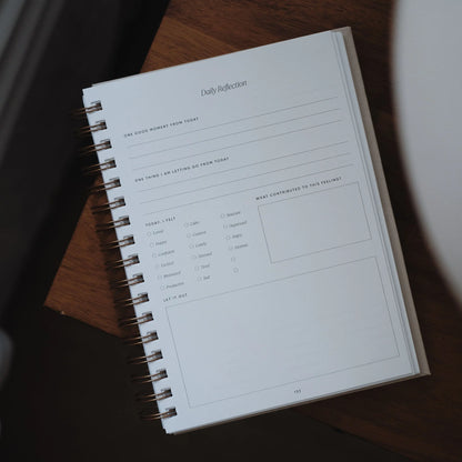 The Inner Work Journal open to a blank daily reflection page on a wooden desk.
