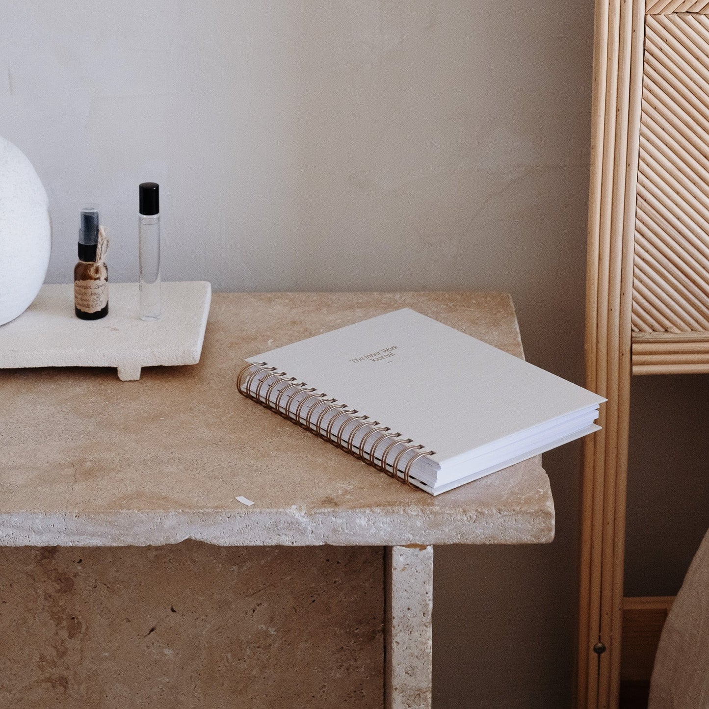 The Inner Work Journal in sand resting on a stone table, styled with minimalist decor including perfume and a neutral background.