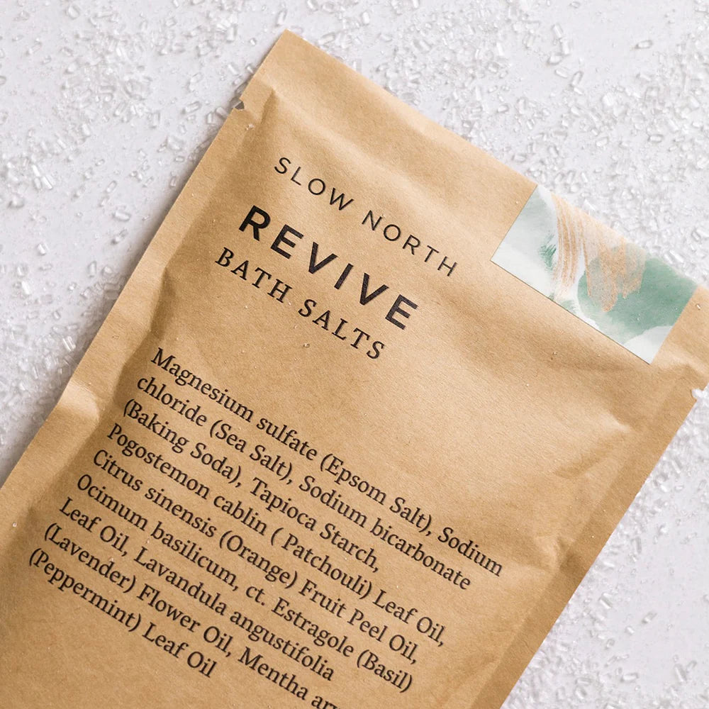 Close-up shot of Slow North Revive Bath Salts packaging, highlighting the ingredients list and natural design details.