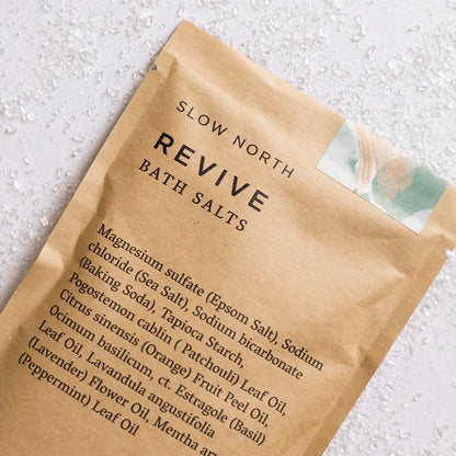 Close-up shot of Slow North Revive Bath Salts packaging, highlighting the ingredients list and natural design details.