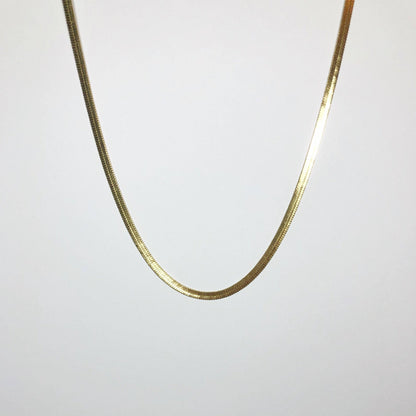 Full-length view of gold snake herringbone chain necklace hanging against white background.