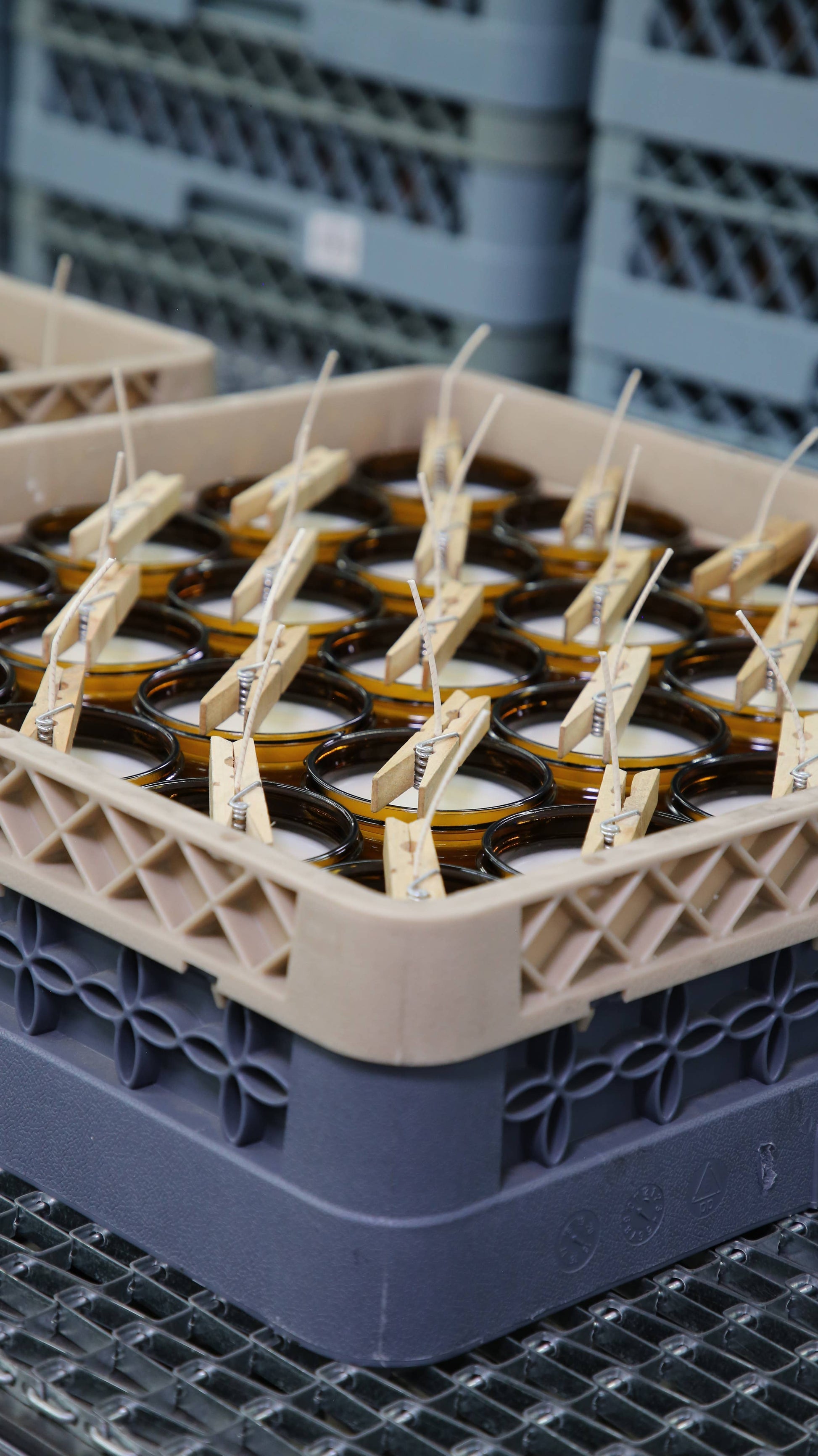 Dozens of P.F. Candle amber jars filled with candle wax and wicks during production process.