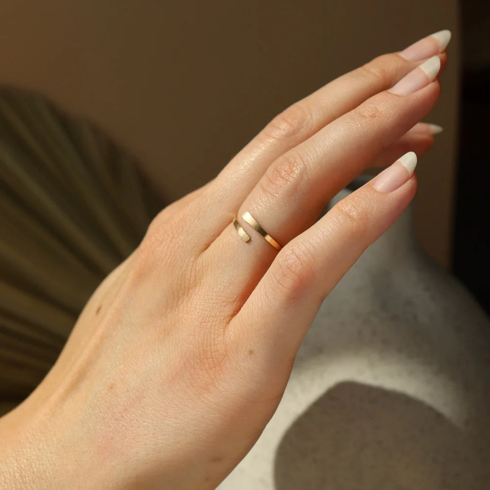 Close-up of Token Jewelry Coil Ring in gold styled on hand.