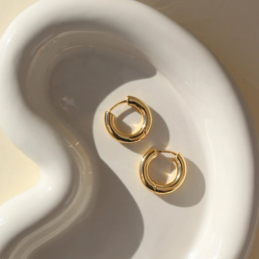 Token Jewelry Everyday Hoops gold earrings styled on a sculptural white dish.
